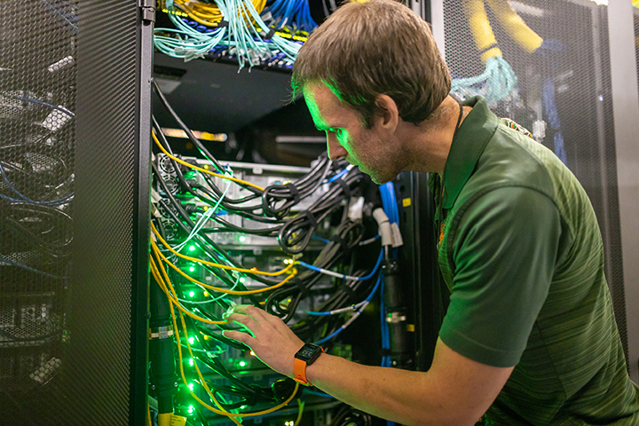 Pedro Davila examines cable connection on a University of Miami supercomputer
