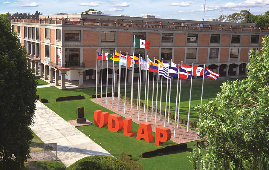 UDLAP aerial showing lawn with international flags on flagpoles in back of large UDLAP orange letters (sculptural) on lawn with college in background