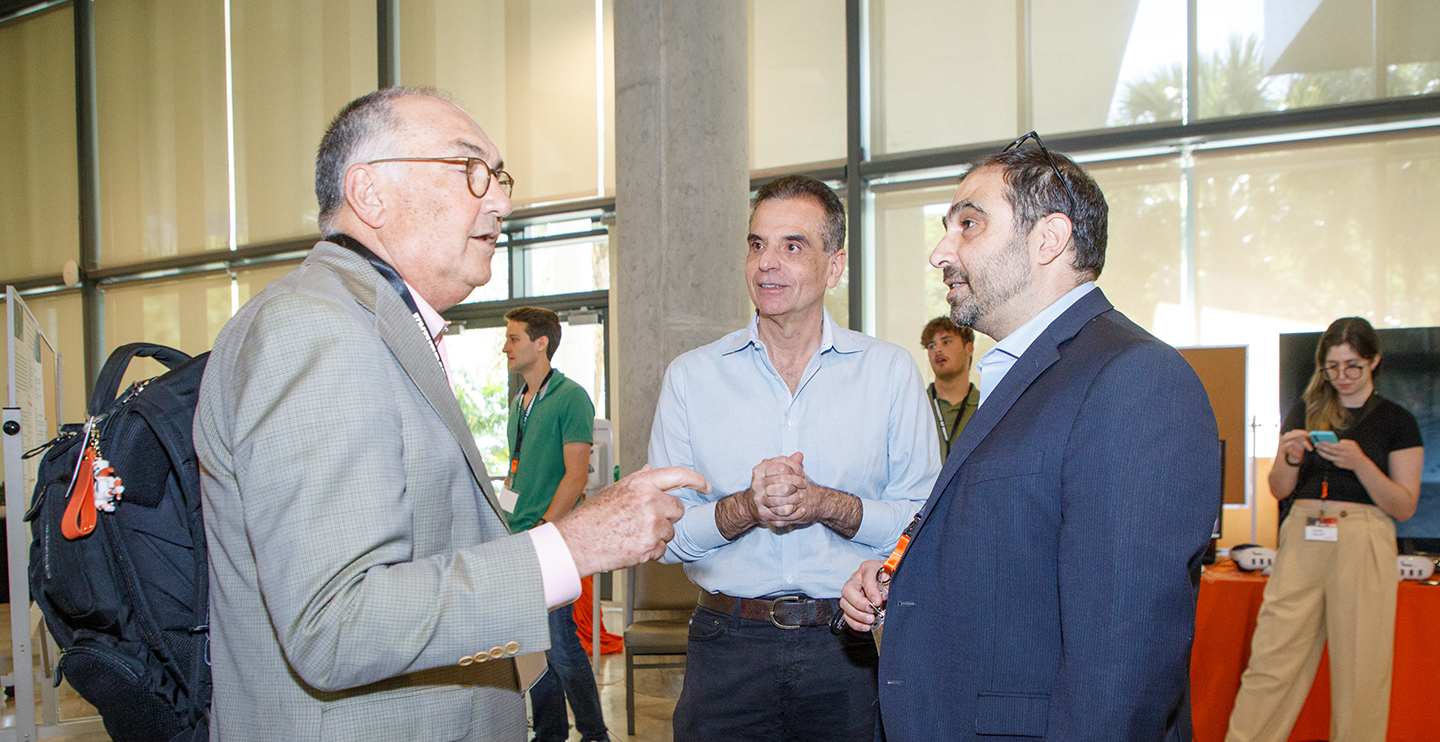 Dr. Tsinoremas (center) chats with Eduardo Alfonso (at left) and Kaan Inal (on right) at IDSC Day