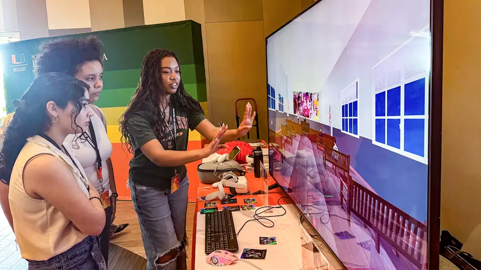 Graduate student in interactive media Ma’at Hetep explains to students Faith Jimenez, left, and Barbara Griffin how the virtual reality murals experience “Telling Overtown Stories, Saying Their Names” works. Photo: Robert C. Jones Jr./University of Miami